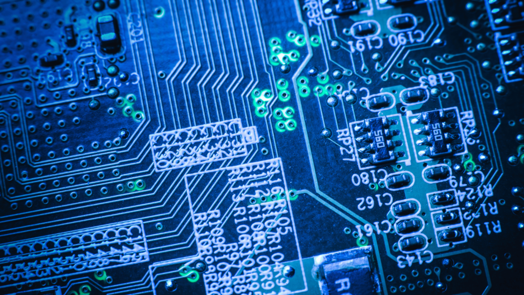 Close-up of an electronic circuit board illuminated by blue lights, showcasing intricate components and intricate wiring.


